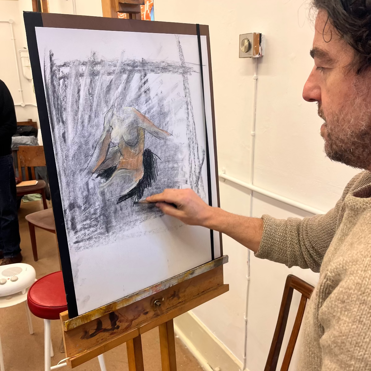 Man painting a woman from life on an easel in a room.