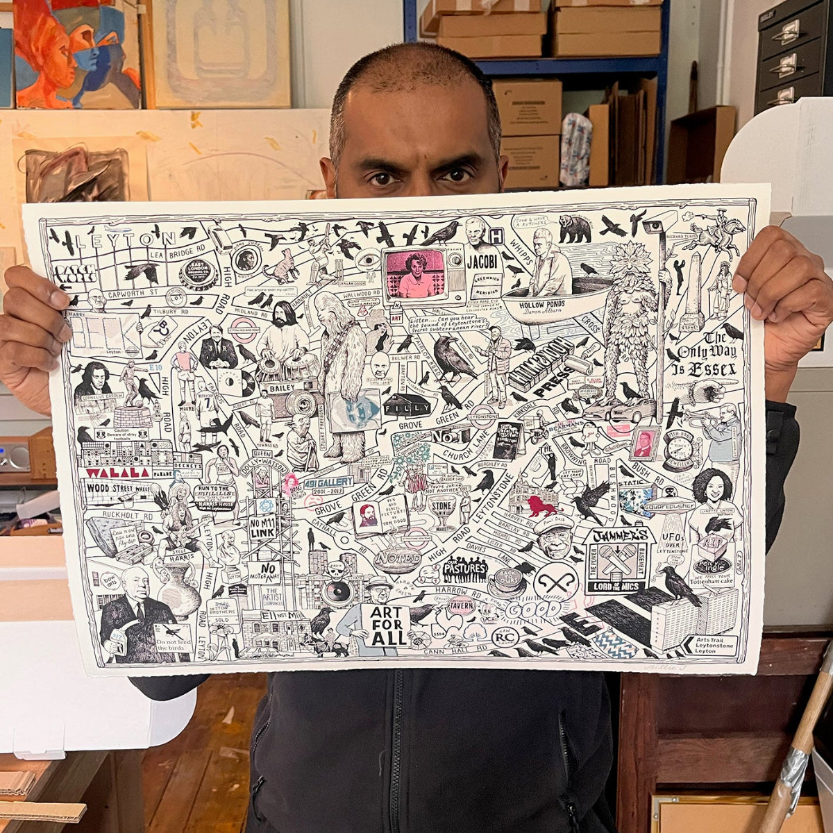 Person holding a large framed artwork with various illustrations and text.