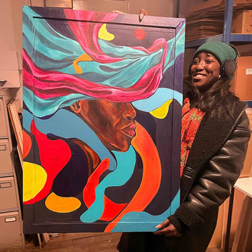 Person holding a colorful abstract painting in an indoor setting