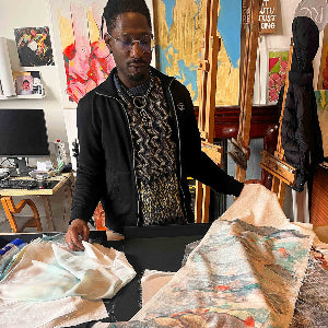 Man in an art studio with paintings and art supplies around