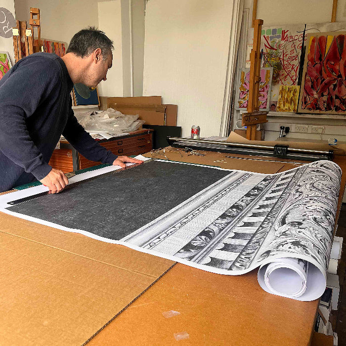 Man working on a large print or artwork in an art studio.