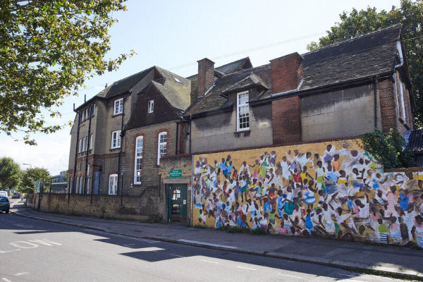Mural on a building wall with people of various colors, set against a clear sky.