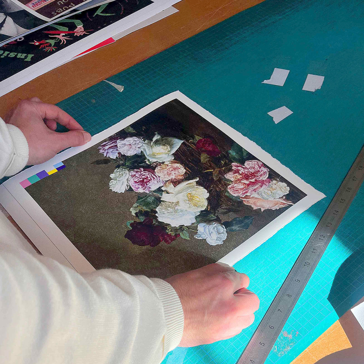 Person working on a floral artwork with a ruler on a green cutting mat