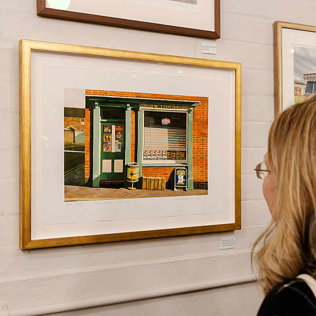 Framed artwork on a wall with a person looking at it