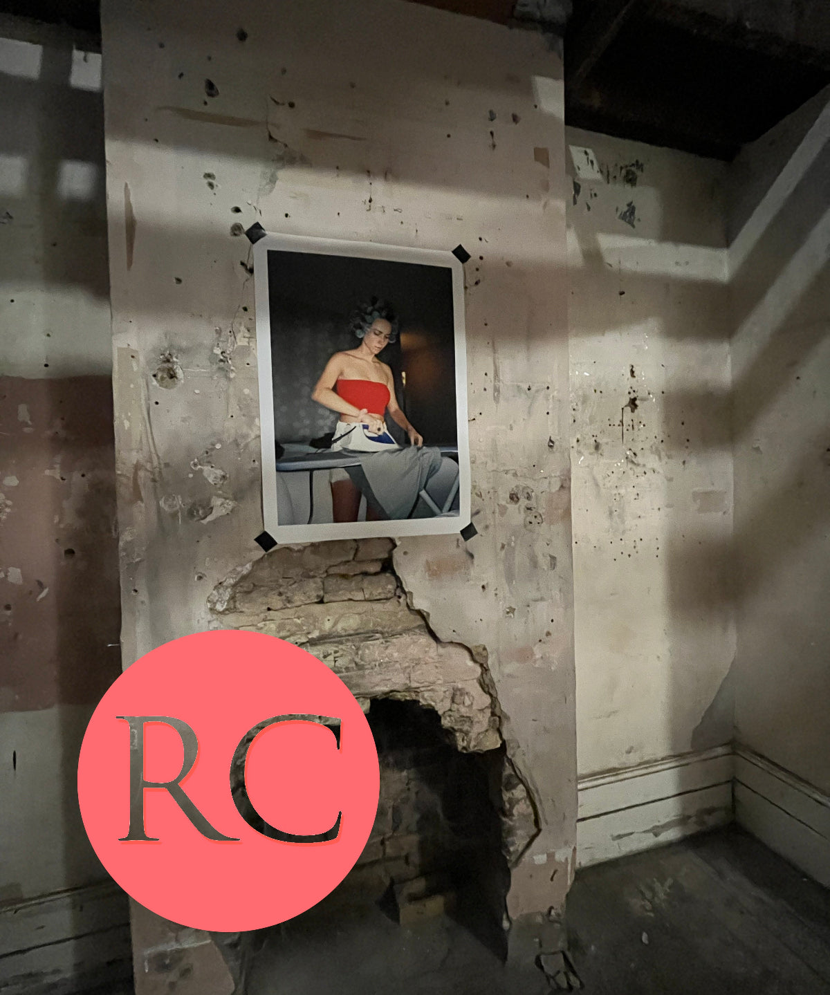 Framed portrait of a woman on a wall with visible damage and peeling paint.