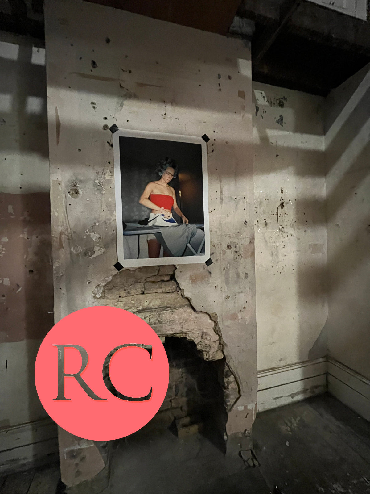 Framed portrait of a woman on a wall with visible damage and peeling paint.